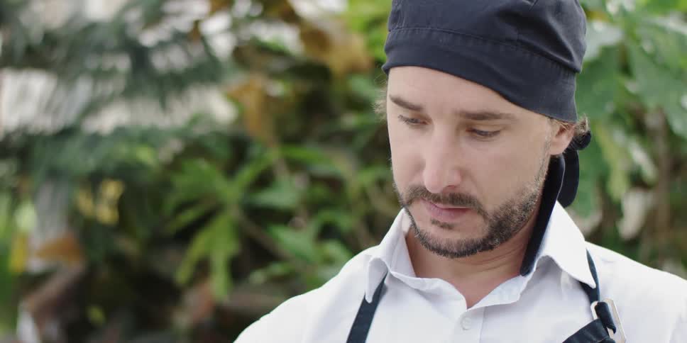 A man wearing a blue hat stands outside