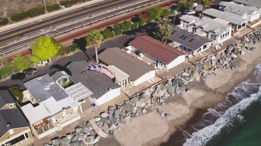 A kite is flying over a beach community during the day