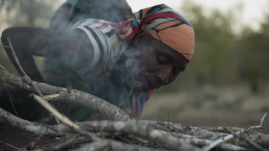 A woman starts a fire on some sticks