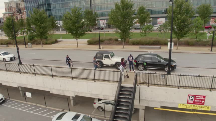 People riding kick scooters in a city as others tend to their own business