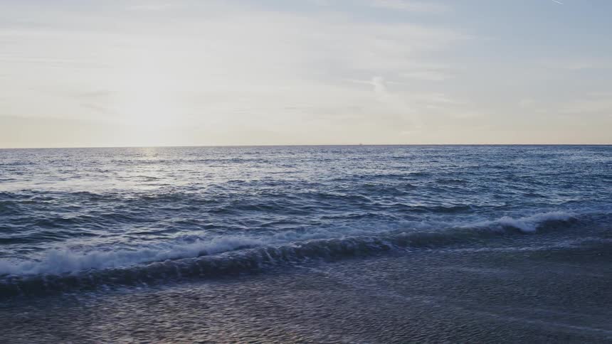 Ocean waves wash ashore at sunset