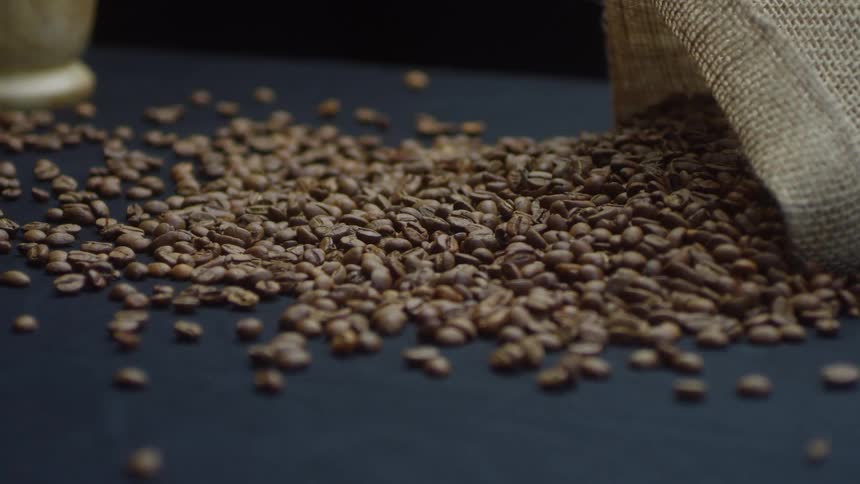 The bag of coffee beans are spilled on the table