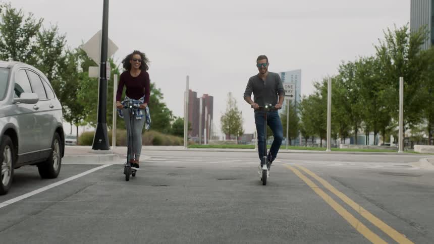 Couple riding kick scooters in a city