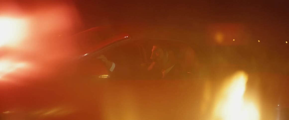 A fire burns next to a man in a car