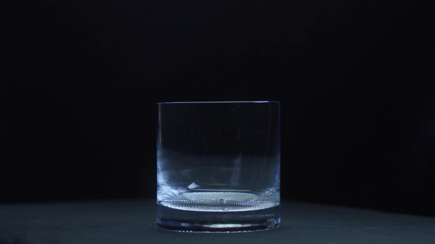 An ice cube is falling into a glass and bouncing