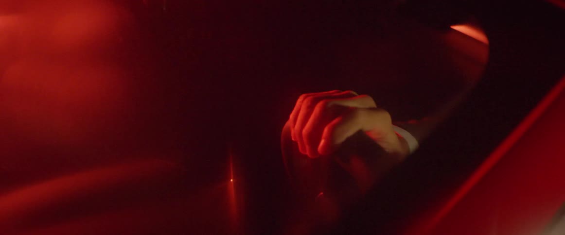 A light glows red as a man holds a car steering wheel