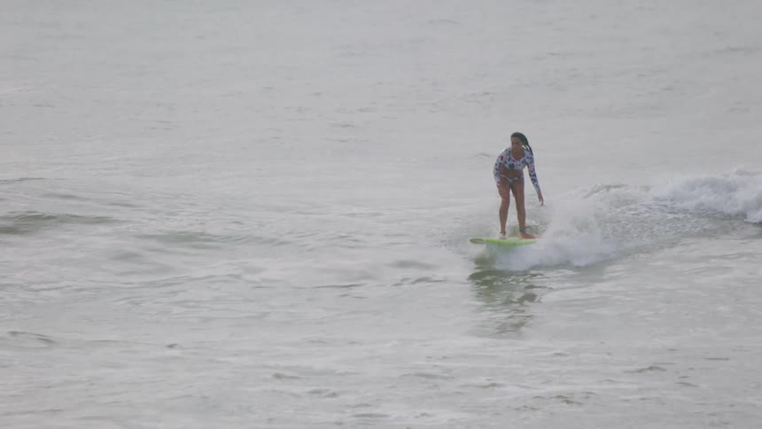 A surfer stands on her board