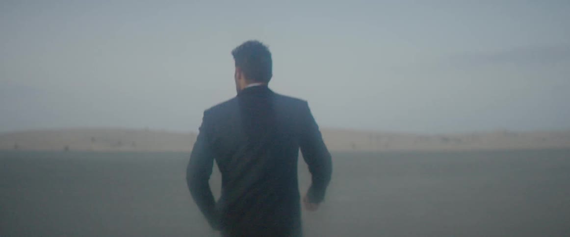 A man in a suit is walking in the desert