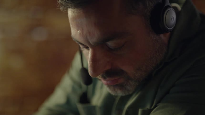 A man talks on a headset and writes something