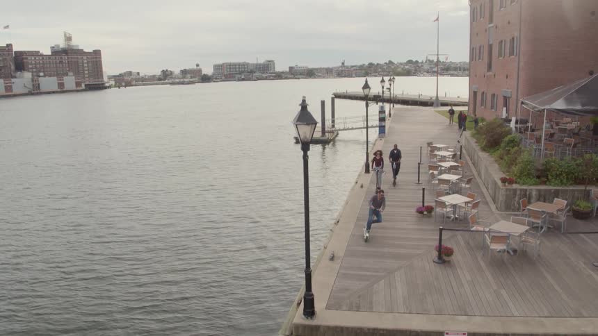 Friends are riding scooters along a boardwalk on a cloudy day