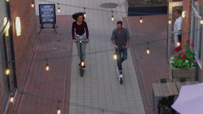 A man and woman have fun riding electric scooters