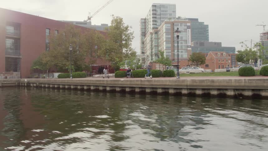 Friends ride scooters on the path of a waterfront city