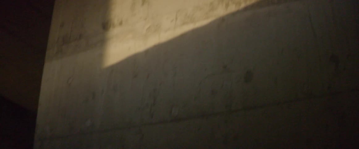 Man casts a shadow while walking in a parking garage