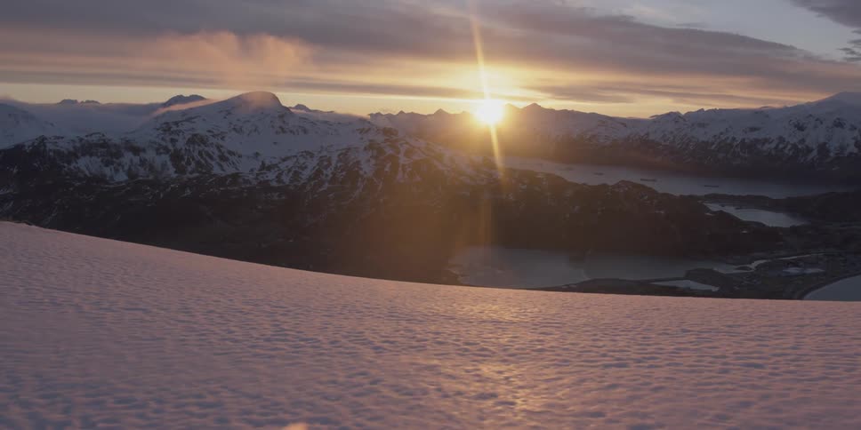 The sun sets over snow capped mountains