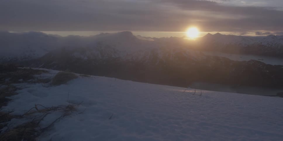 The sun sets over snow covered mountains