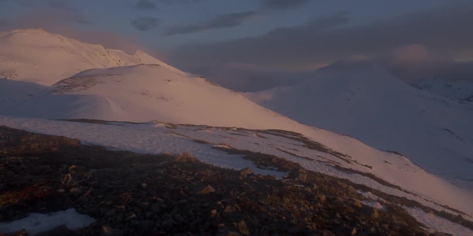 Clouds are hanging over snow-covered mountains at dawn