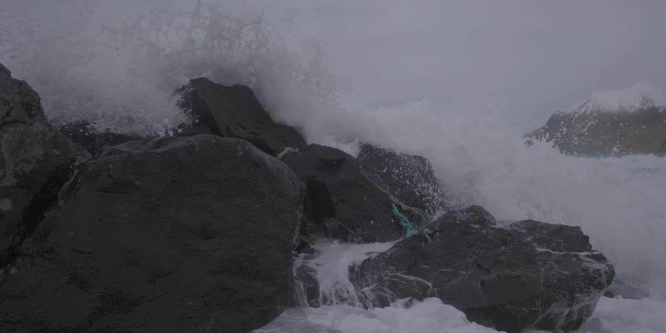 Waves crashing upon a rocky shore on a cloudy day