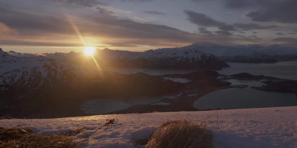 The sun is setting behind a snowy mountain