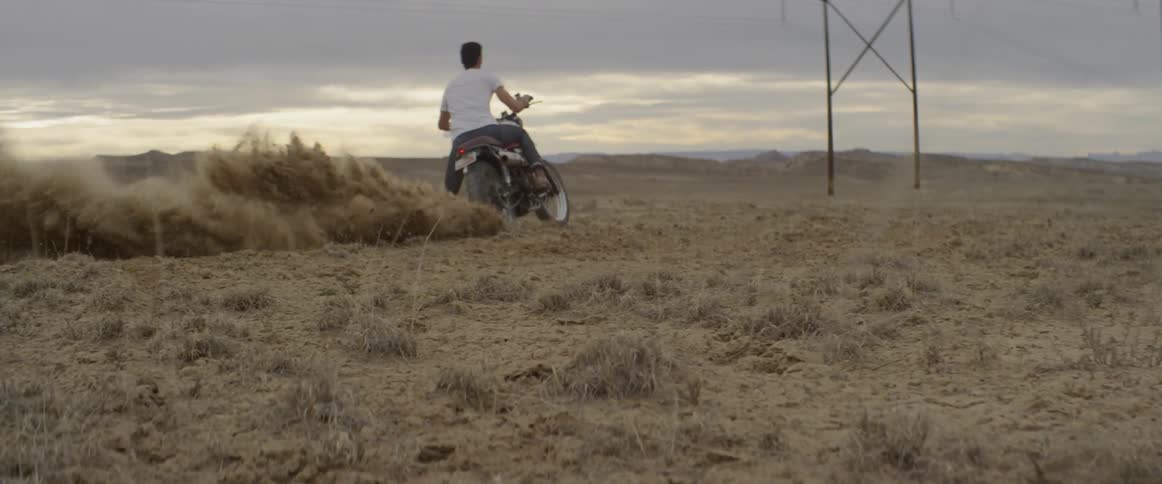 Man kicking up dirt in a field from his motorcycle