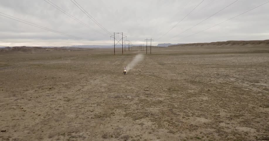 A motorcycle races down the barren field