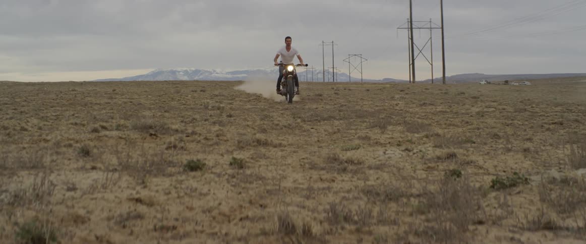 A motorcyclist rides across a rural field