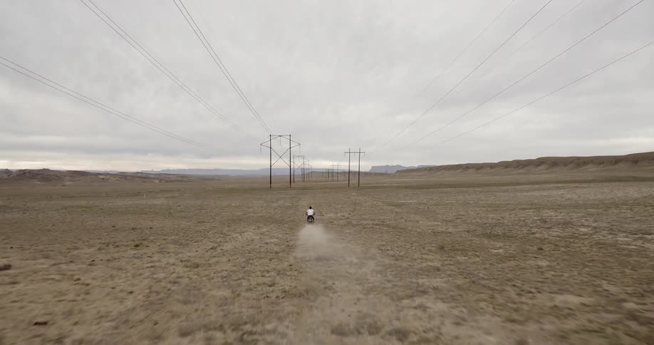 Someone drives a motorcycle between power lines