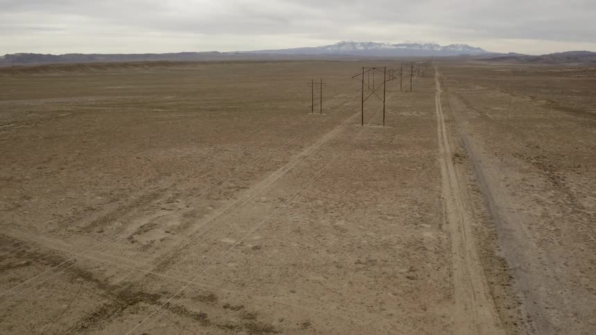 Power lines stand in a rural dirt field