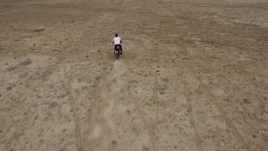 A motorcyclist rides across a rural field