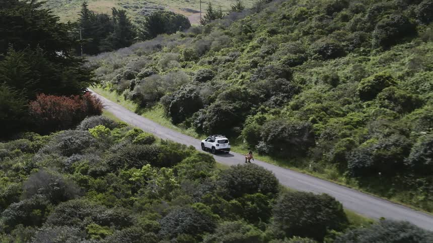 Car pulls man on skis on a mountain road