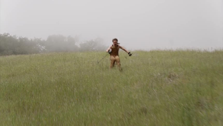 Man skiing down a grassy hill on a hazy day