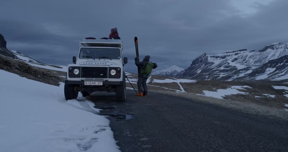 People loading skis on to roof of an SUV