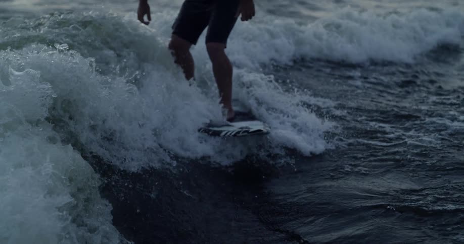 Person surfs small waves in the evening