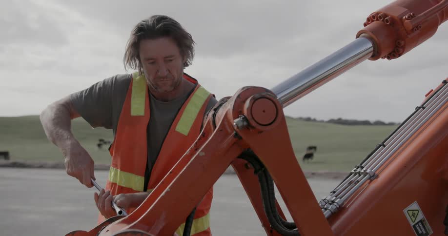 Construction worker fixes machinery in a rural area