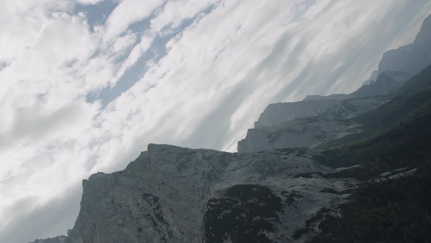 Clouds over jagged snow capped mountain peaks