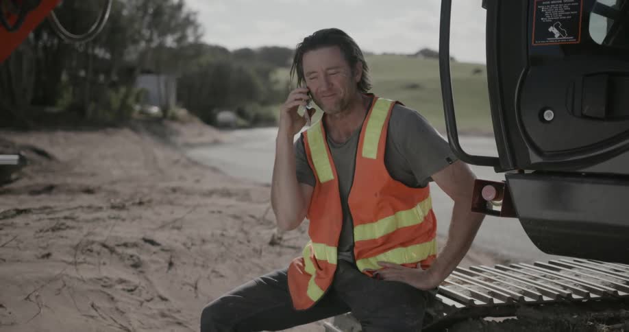 A construction worker talks on a cell phone