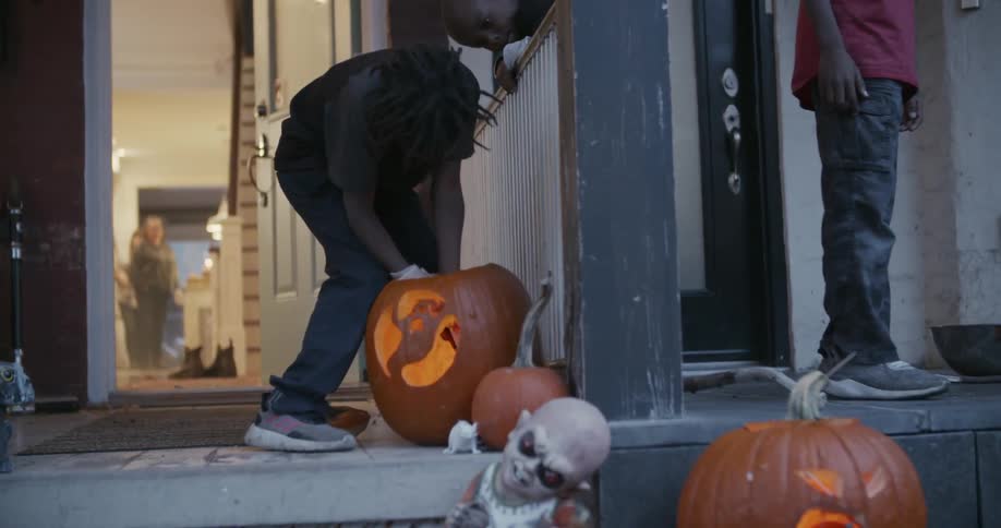 A young boy lights a candle inside a pumpkin