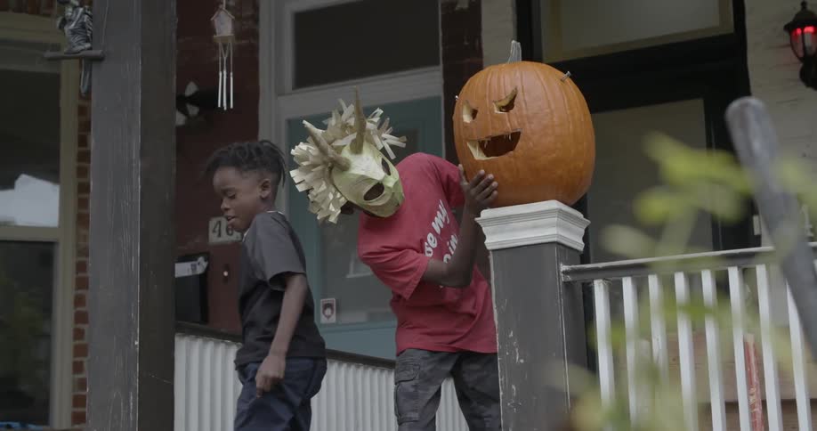 Boys are decorating their front porch with a jack-o'-lantern