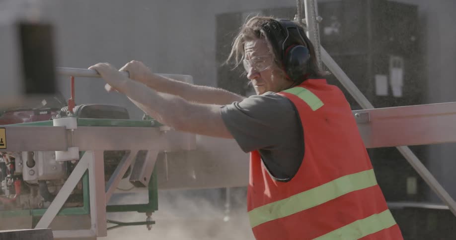 A man guides a piece of equipment and gives instruction to others