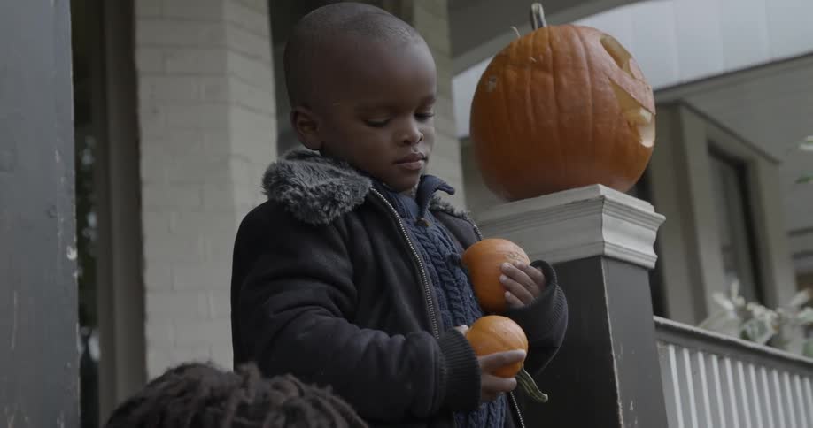 A young boy holds two small pumpkins