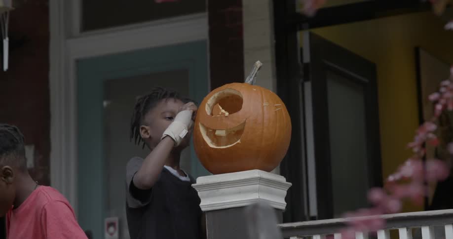 A young boy touches a carved pumpkin