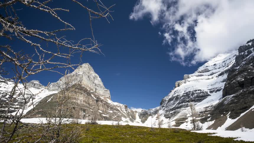 Panorama of a tall mountain top covered with snow and surrounding clouds in Banff National Park
