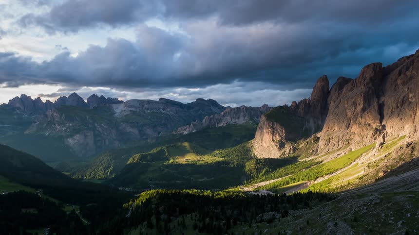 Dark clouds hang above the valley between mountains