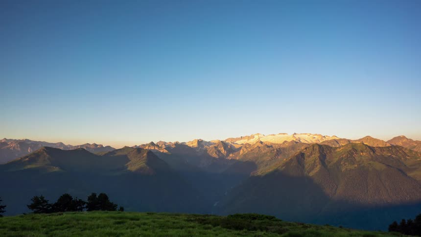 The sun rises and soft pink light moves over the mountain