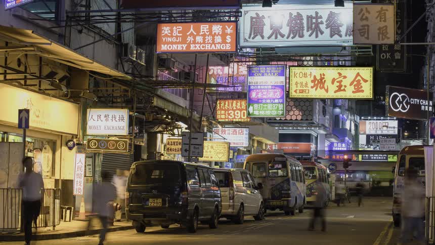 Pedestrians and vehicles travel on a city road at night