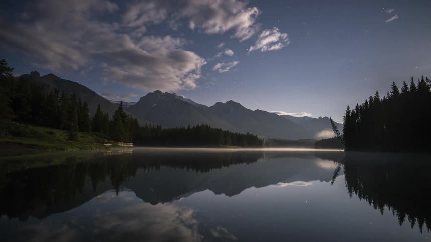 The Johnson Lake is calm at moonlight in Banff National Park