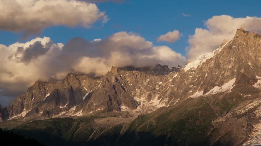 Fluffy white and gray clouds hang above the mountain top