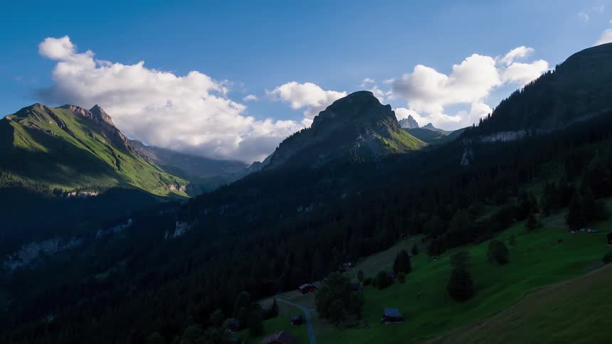 Shadows are covering hillsides in a mountain range during the day