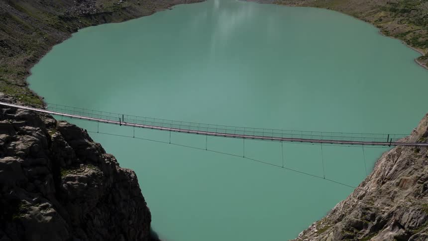 A perfect green lake in the middle of mountains with a bridge over it