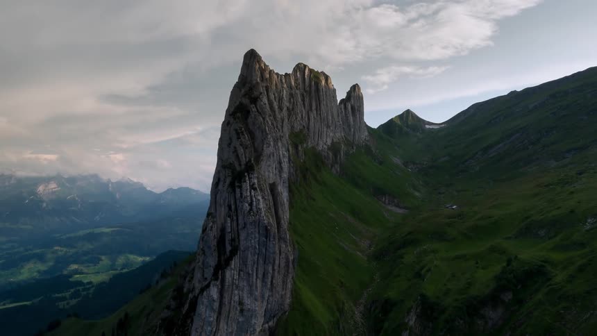 Clouds hang above tall stone mountains
