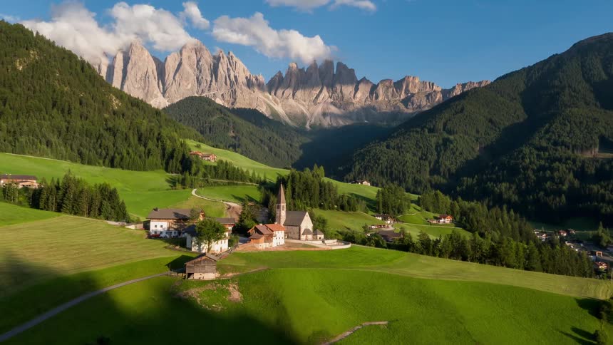The sun shines on a church in a mountain valley